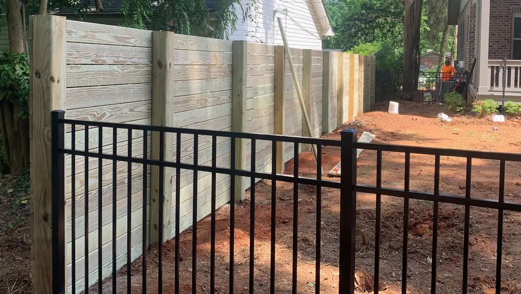 Horizontal wood privacy fence meeting black aluminum fencing on a completed Statesville job