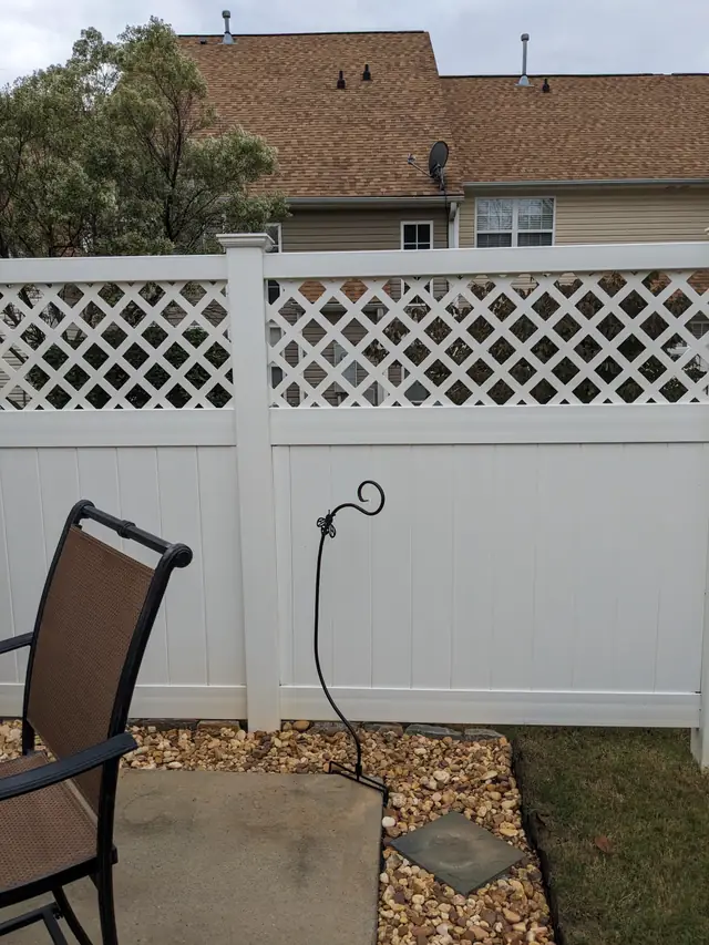 A white vinyl fence finished with a decorative lattice top along a property line